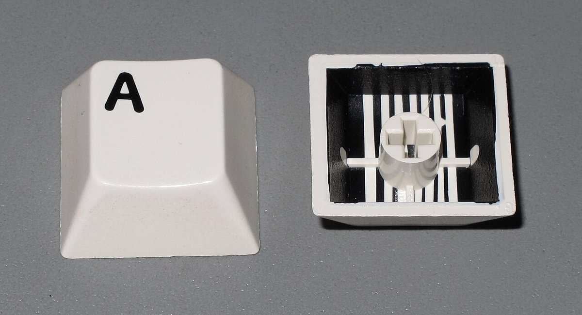 Hai keycap đúc hai lớp nhựa, một chiếc màu trắng in chữ A và một chiếc màu đen nhìn từ mặt dưới