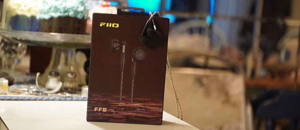 Hộp đựng FiiO FF5 màu đen in hình tai nghe, có cặp tai nghe treo bên cạnh